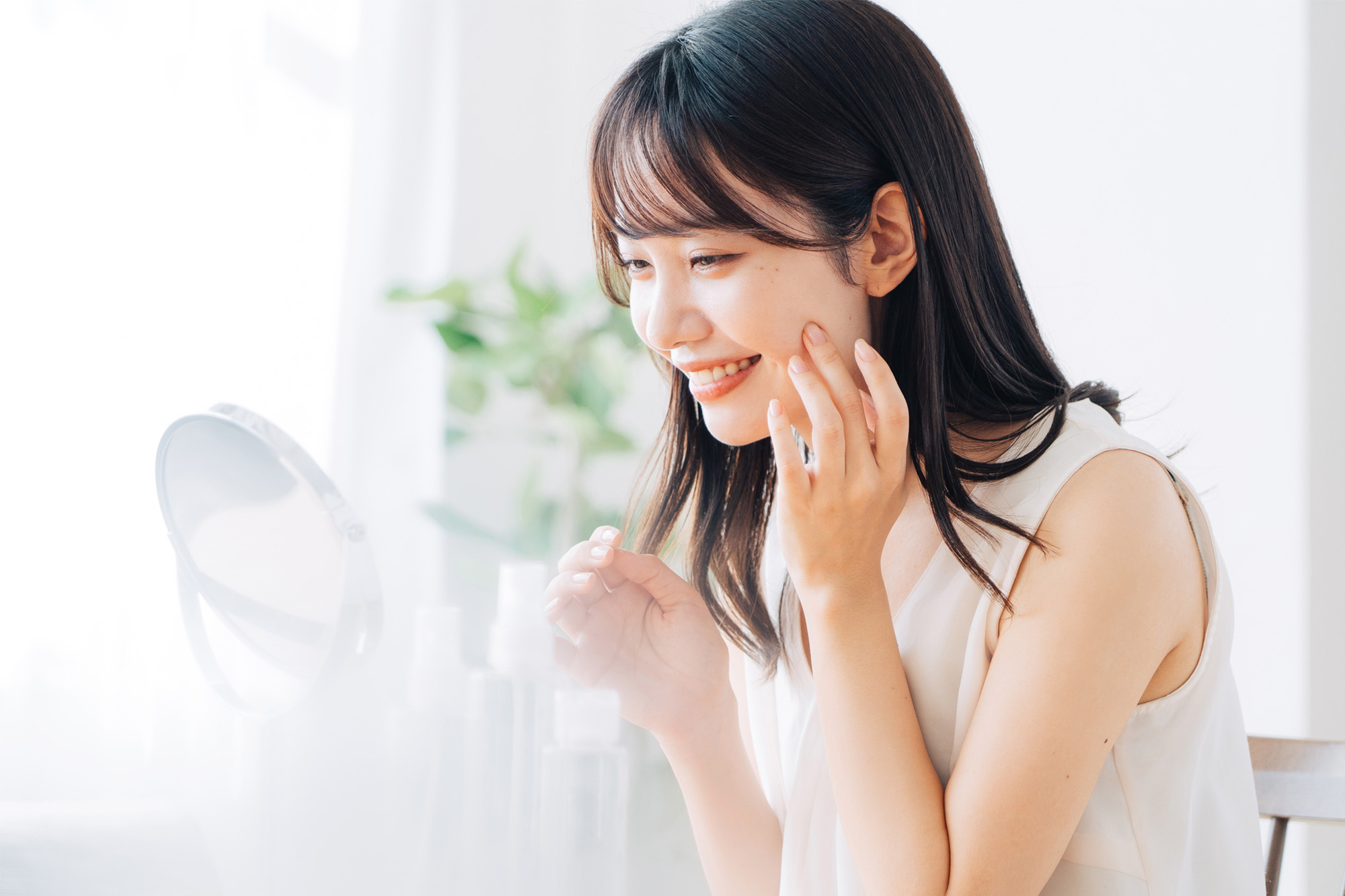 鏡を見ながらスキンケアをしている女性