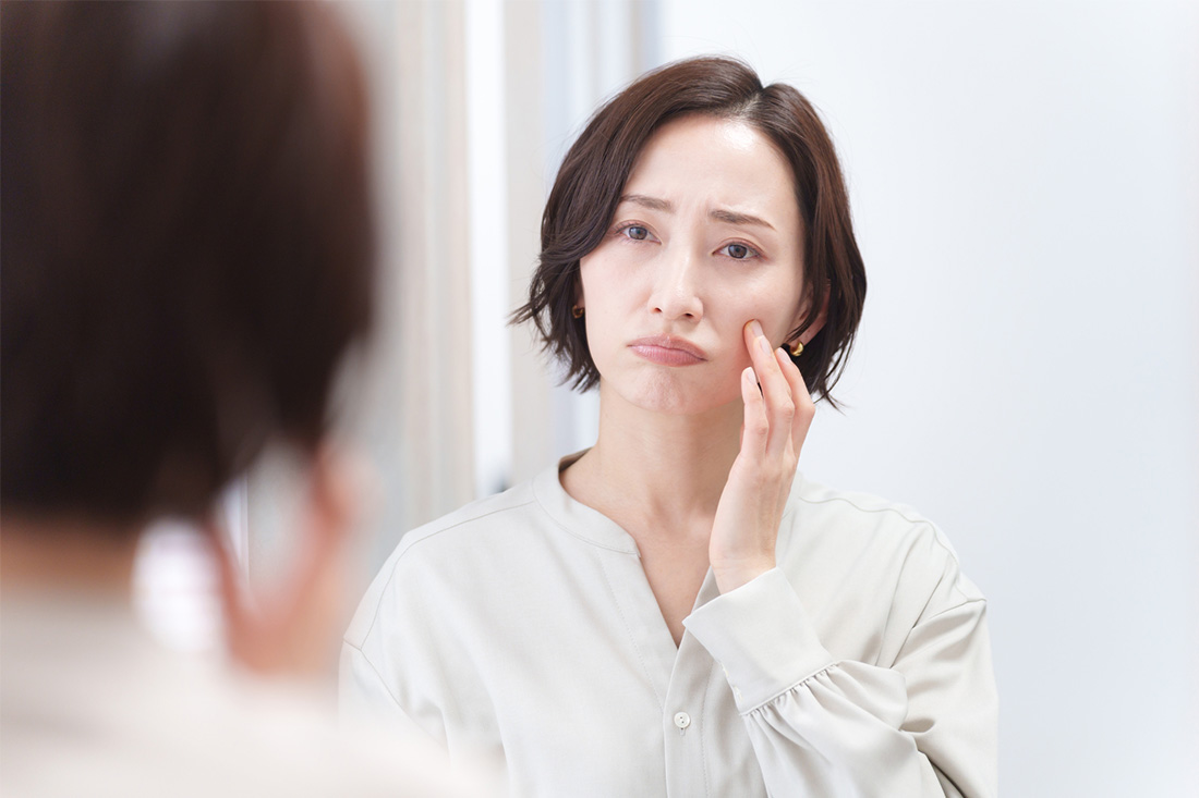 鏡をみながら、肌にできたシミを気にする40代女性