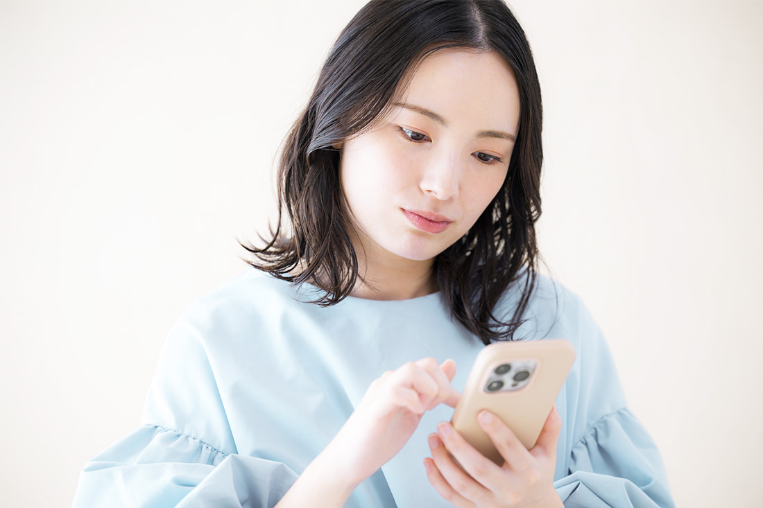 スマートフォンでシミのメカニズムについて調べている女性