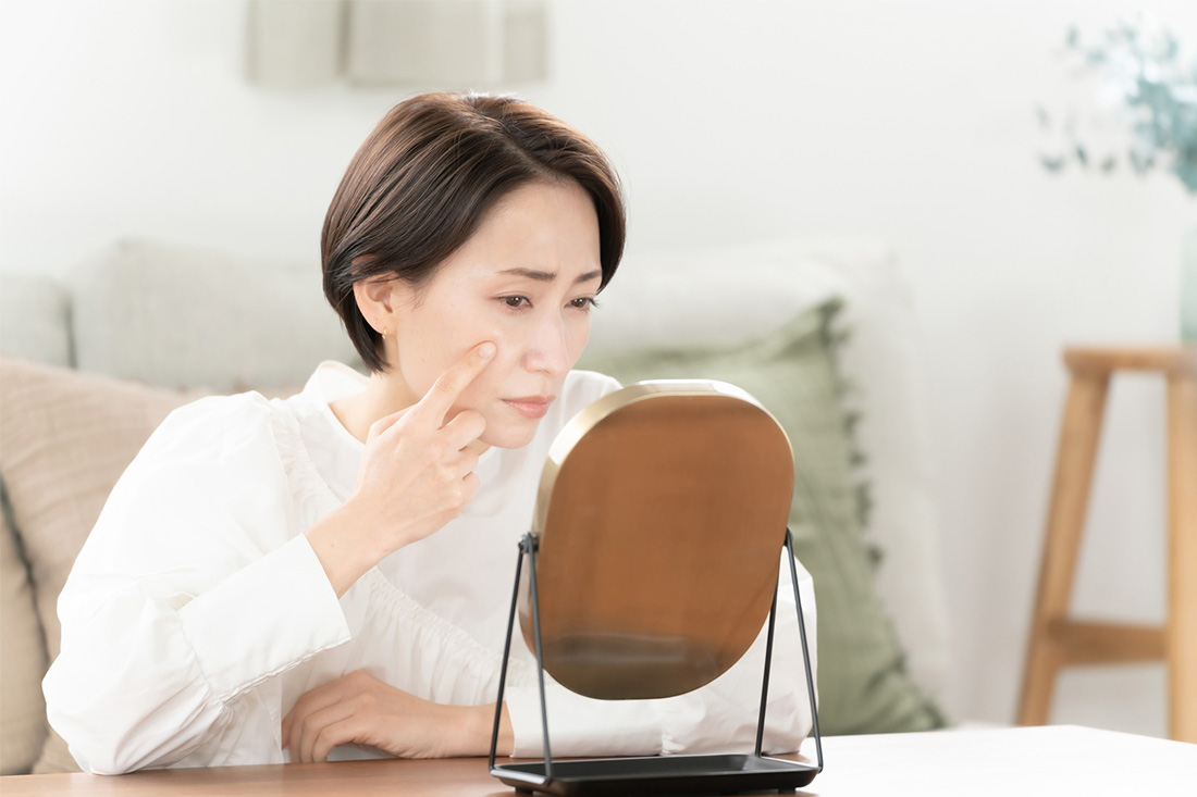 鏡を見て肌を気にする女性