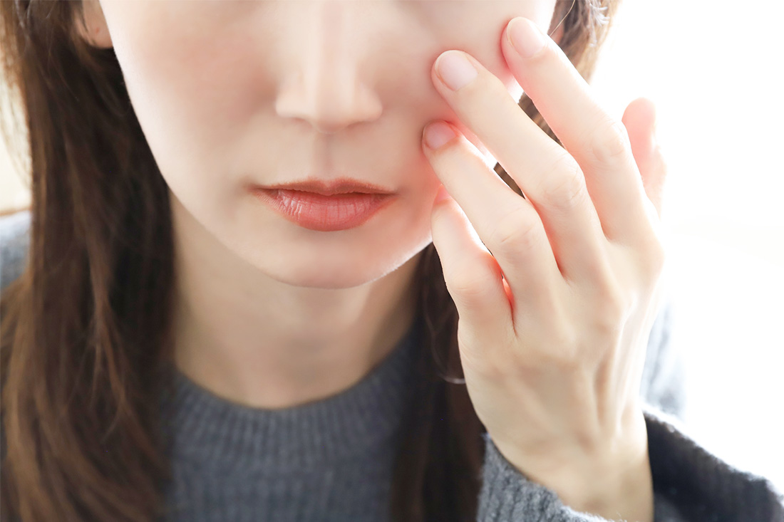 シミを気にして頬を触る女性