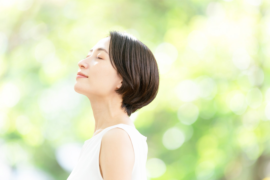 陽射しの眩しさで目を瞑る女性